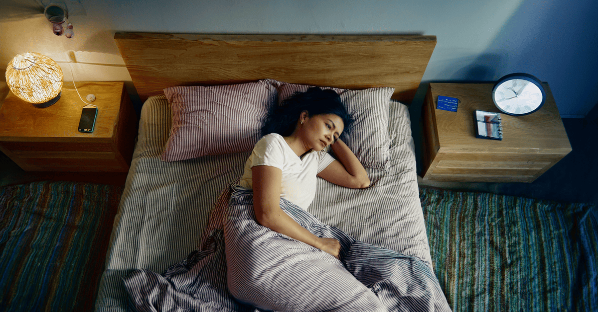 Indian adult sleeping on their side with head elevated in a calm, clutter-free bedroom